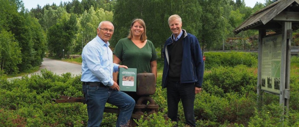 Forfatter Ingulv Burvald, kommunikasjonssjef Cathrine W. Eidal og bransjesjef Runar Rugtvedt ved en gammel pumpe brukt i den tidligere bergverksdriften. Forfatteren har selv trukket pumpa ut fra skogen!