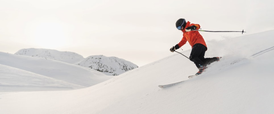 Skiløper på vei ned en snøkledd fjellside